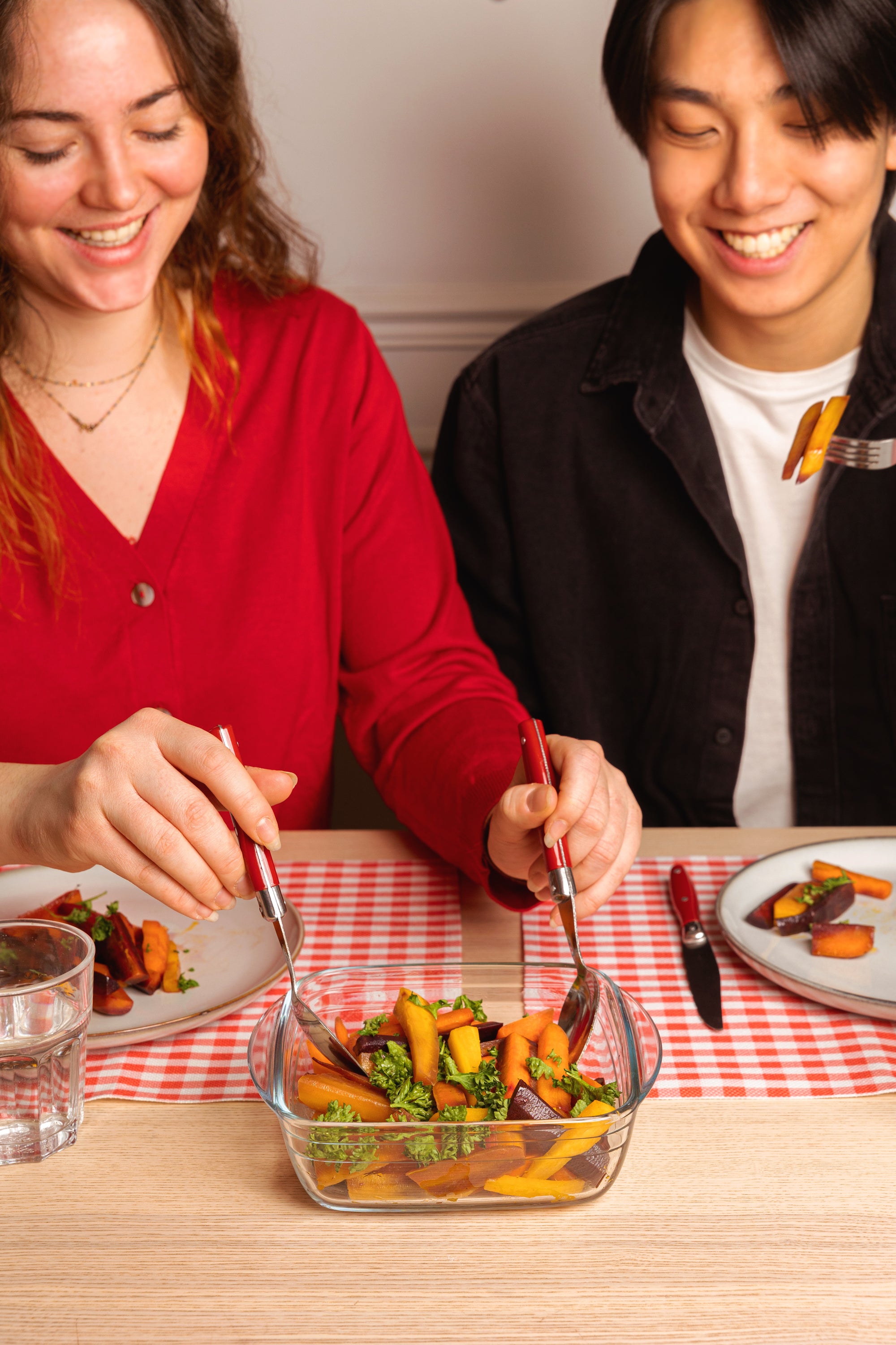 Two people enjoying a meal made in ÔCuisine square roaster together at a table with a checkered tablecloth.