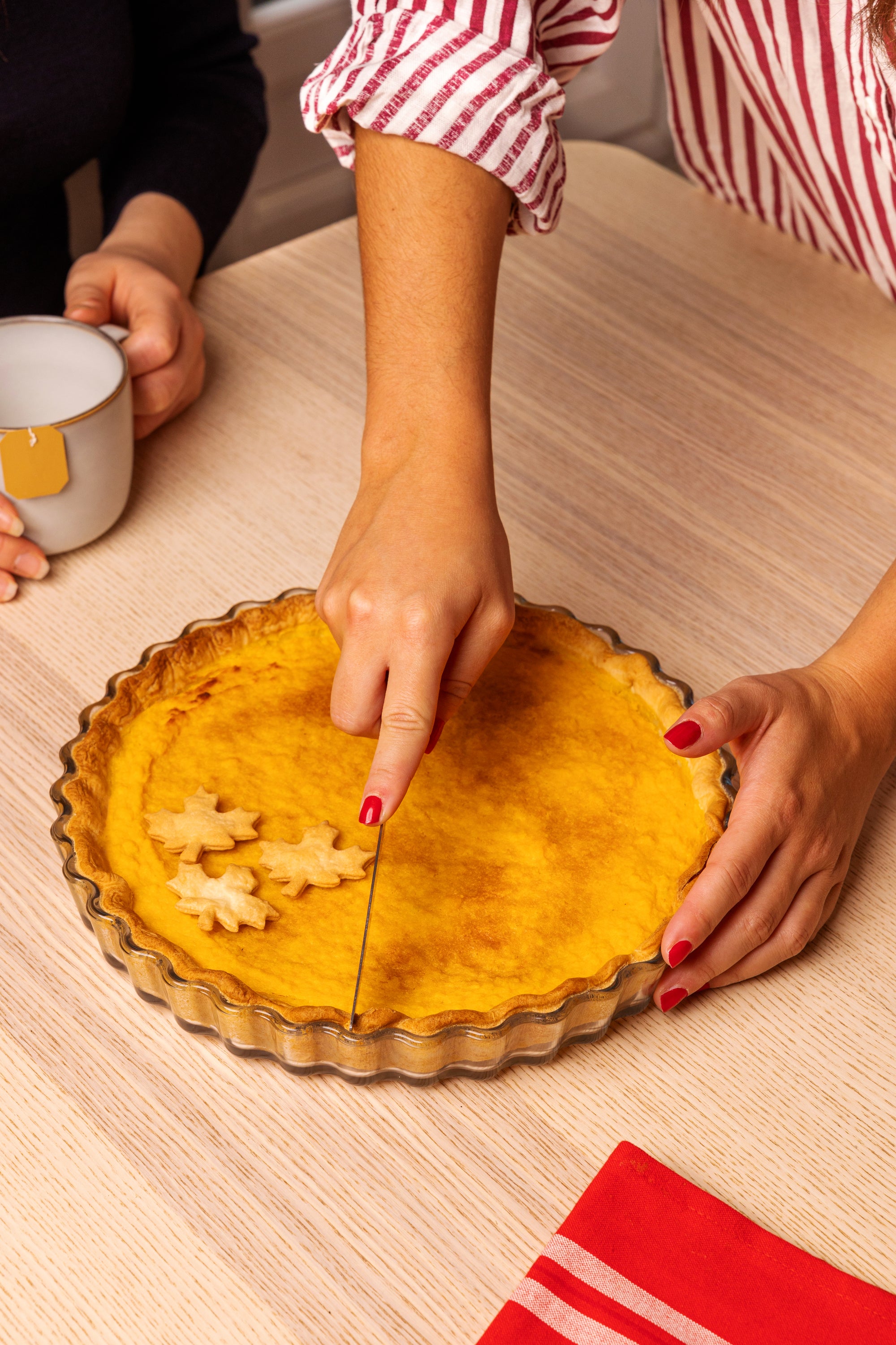 Person cutting a pie iwhich is in an ÔCuisine round flan dish with cookie cutters on a wooden table