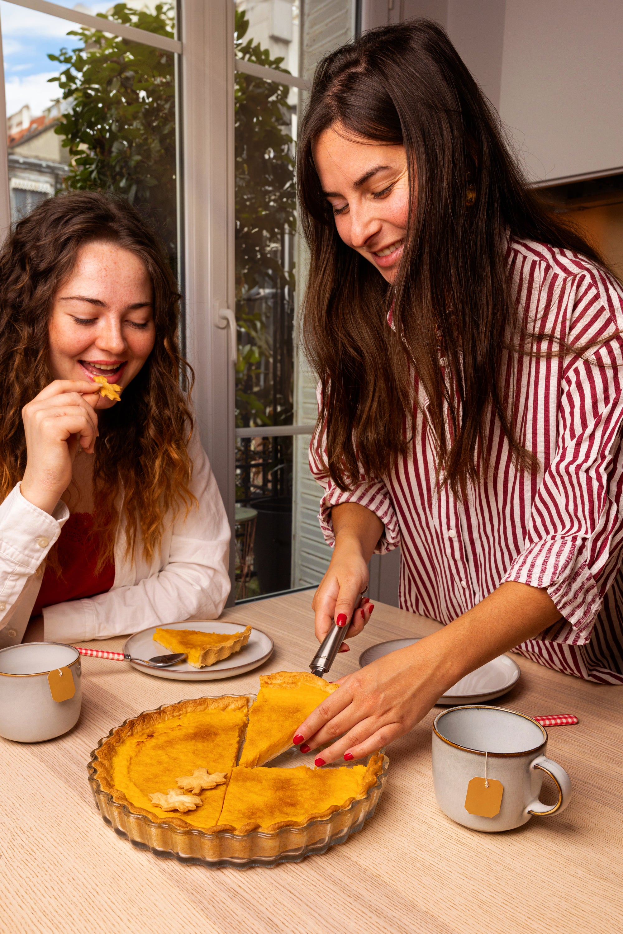 Two women enjoying pumpkin pie placed in an ÔCuisine round flan dish and tea at a table.
